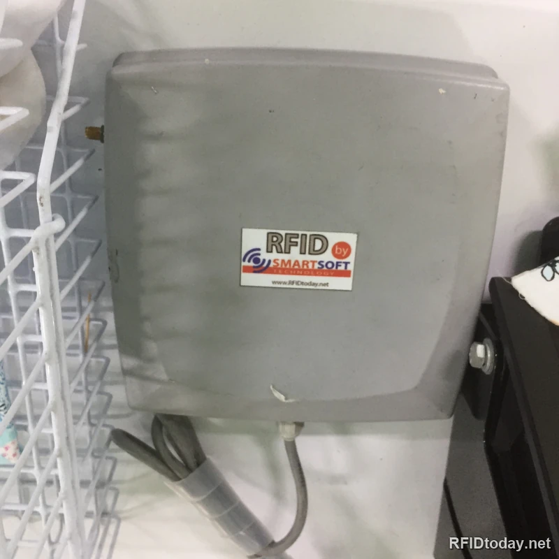 เครื่องอ่านเขียน RFID แบบตั้งโต๊ะ ตัวเครื่องสีเทาพร้อมสายสัญญาณ ติดสติกเกอร์ RFID by Smartsoft Technology และที่อยู่เว็บไซต์ RFIDtoday.net